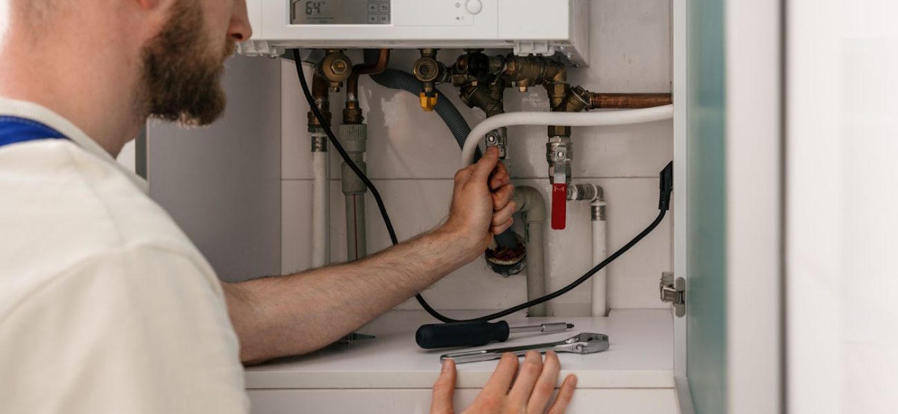 Repairman shut off valve on pipeline, conduct maintenance on gas boiler in a modern bathroom. He focused on checking connections and adjusting settings for optimal performance and energy efficiency SSUCv3H4sIAAAAAAAACpyRTW6DMBCF95V6B+R1kGxAIHqVqIvBHsCKY0e2SVVFuXv9A8jr7phvZp7fY16fH1VFJnCSk6/qFatQS6U25y14aXTA9LJzi1qgLcnTtj0tAciyQiG9sRJUCSfwfNVwxwD1plTE79QkzoPfHLroZUccPC5BI8NTIhu+5ro6GqkZNkKLkEvB3DYldqAs/q/N/PF9Bl5Q899kuAhiUSHkINc8Sm4/Hu29jAabkKZI9TQcVBxoC6WHlVzqpVgzfk1HONa42bS30cLpnChjHjCp+IvnoIkHX8G5MC4OXjzEw8nNvXhHG58C7KpEhEvEkrUdbWnX0XEYKRv6ge4D+XqrDDrJziEUan6ToowuowPS9QKbiU01BTHU3cyaGljPa9aP3djPM0LDwo9//wEAAP//AwBBZLiqpgIAAA==